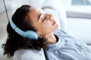 Teen lays on couch and listens to music on her headphones as part of her music therapy