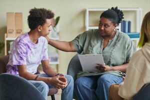 A young man is meeting with a therapist while in the teen alumni program.