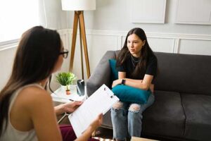 A teen girl is working with a therapist who is utilizing cognitive-behavioral therapy in their session.