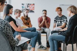Teens are sitting in a circle and being led in a group session of dialectical behavior therapy.