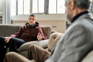 A therapist and a young man use motivational interviewing as a treatment modality during a therapy session.
