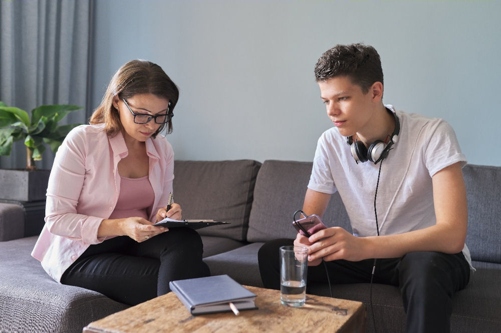 a therapist doing paperwork with a teen boy